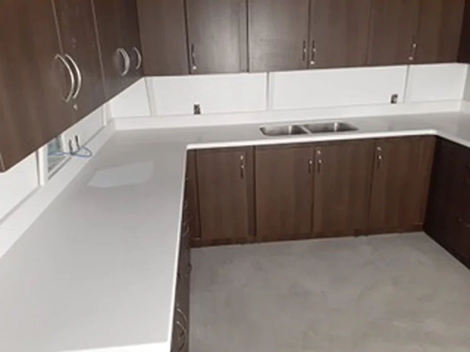 a kitchen with white countertops and dark wood cabinets