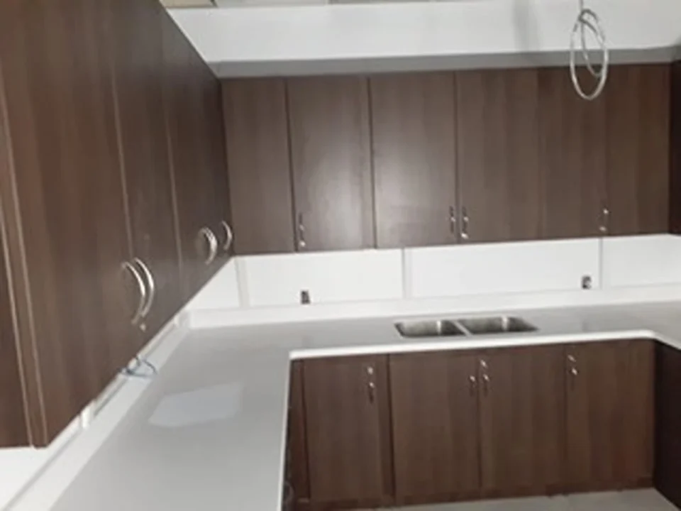 a kitchen with dark wood cabinets and white countertops