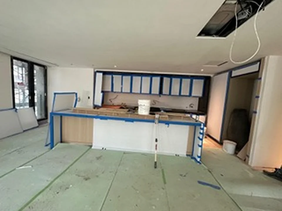 a room with a kitchen and a white bucket