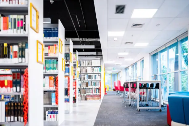 a room with shelves of books and tables