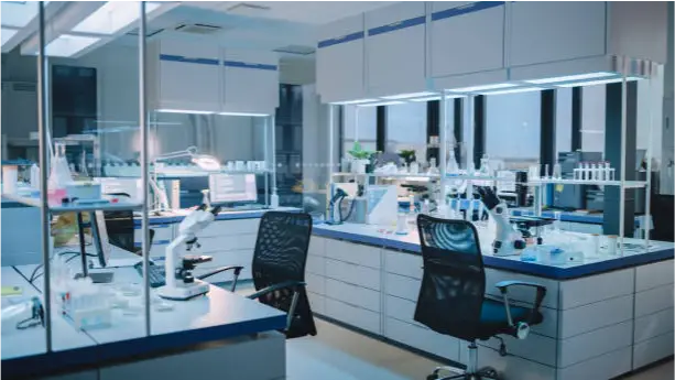 a room with white cabinets and a desk with microscopes and a lamp